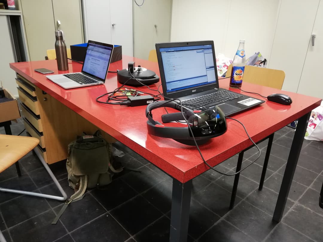 Desk with two laptops and a HoloLens on it.
